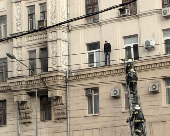 В центре Харькова пьяный мужчина вылез на карниз стены дома (фото)